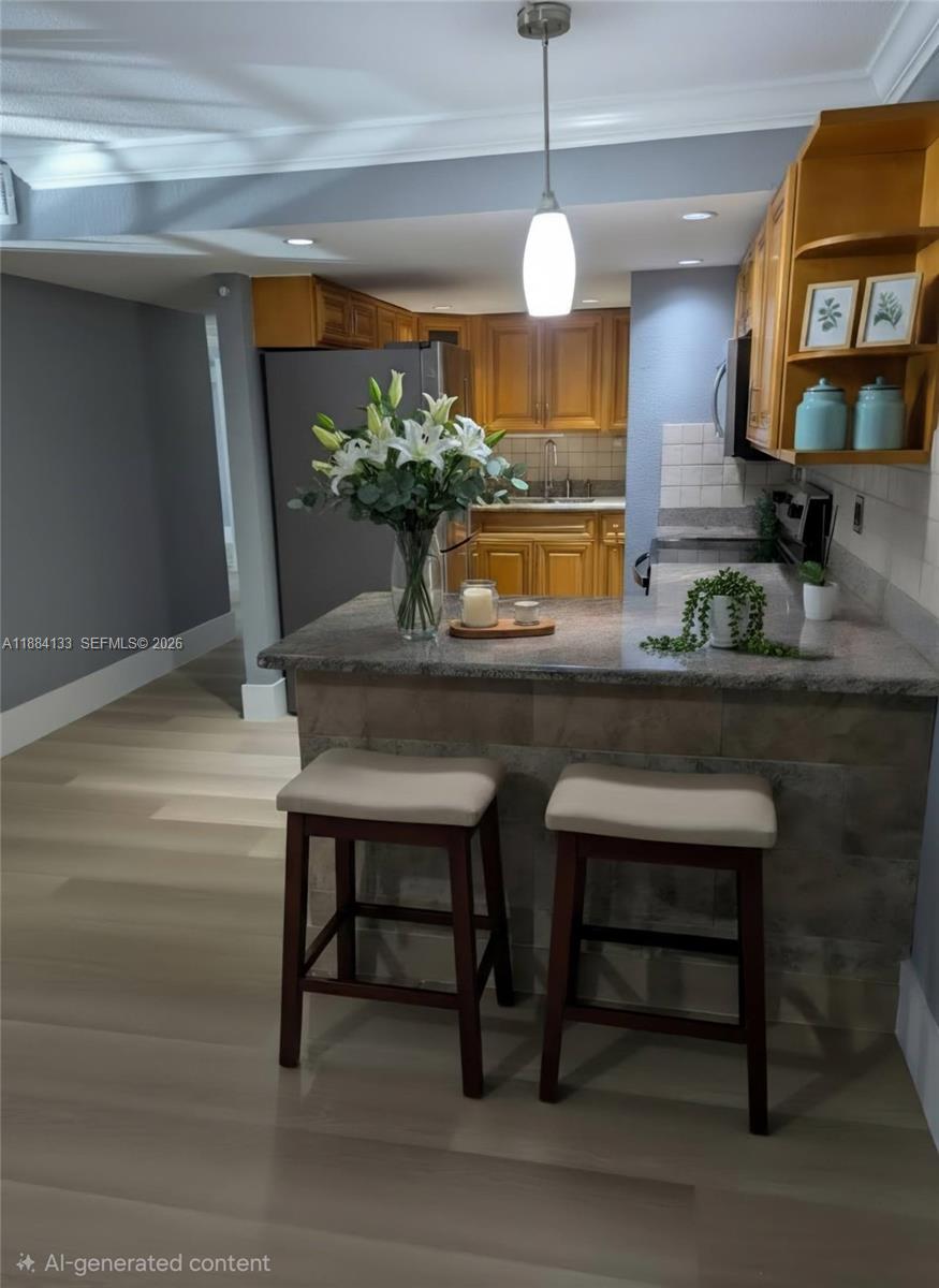 This kitchen features wooden cabinets, a granite-topped breakfast bar with two stools, and light flooring — 13700 SW 62nd St # 204, Miami FL 33183, MIAMI, FL
