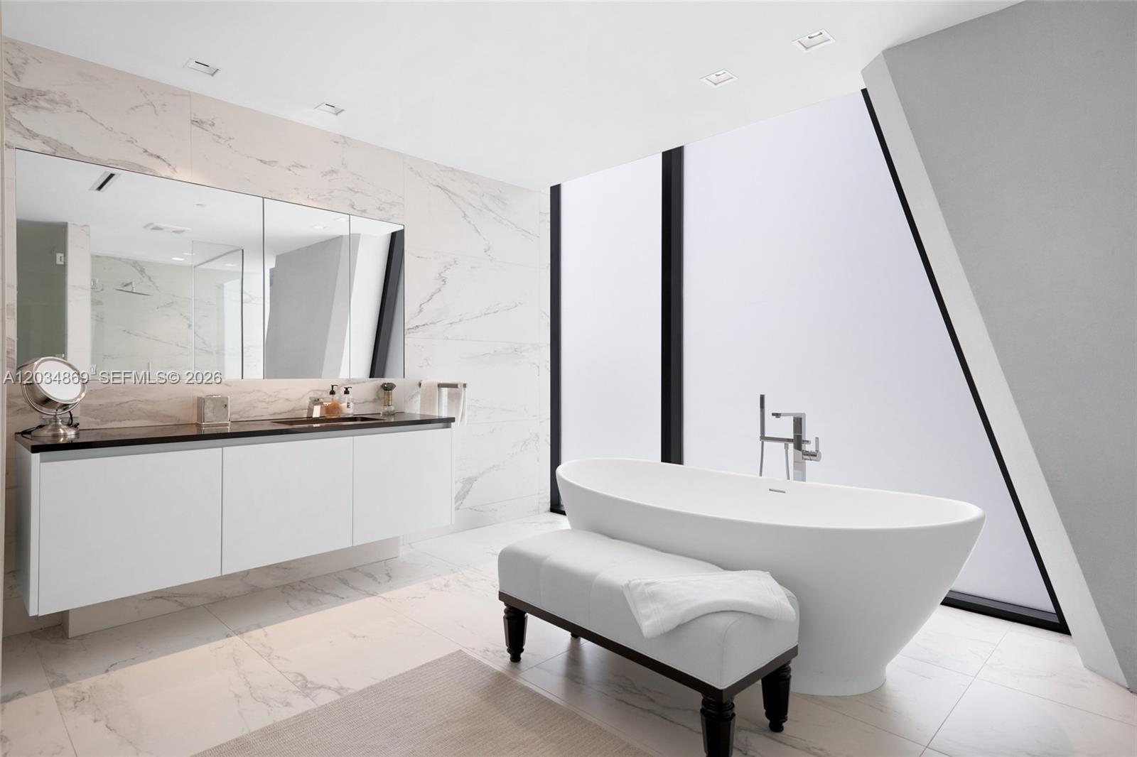 A modern bathroom features a white soaking tub, a floating vanity, and marble tile walls — 1000 Biscayne Blvd # 3701, Miami FL 33132, MIAMI, FL