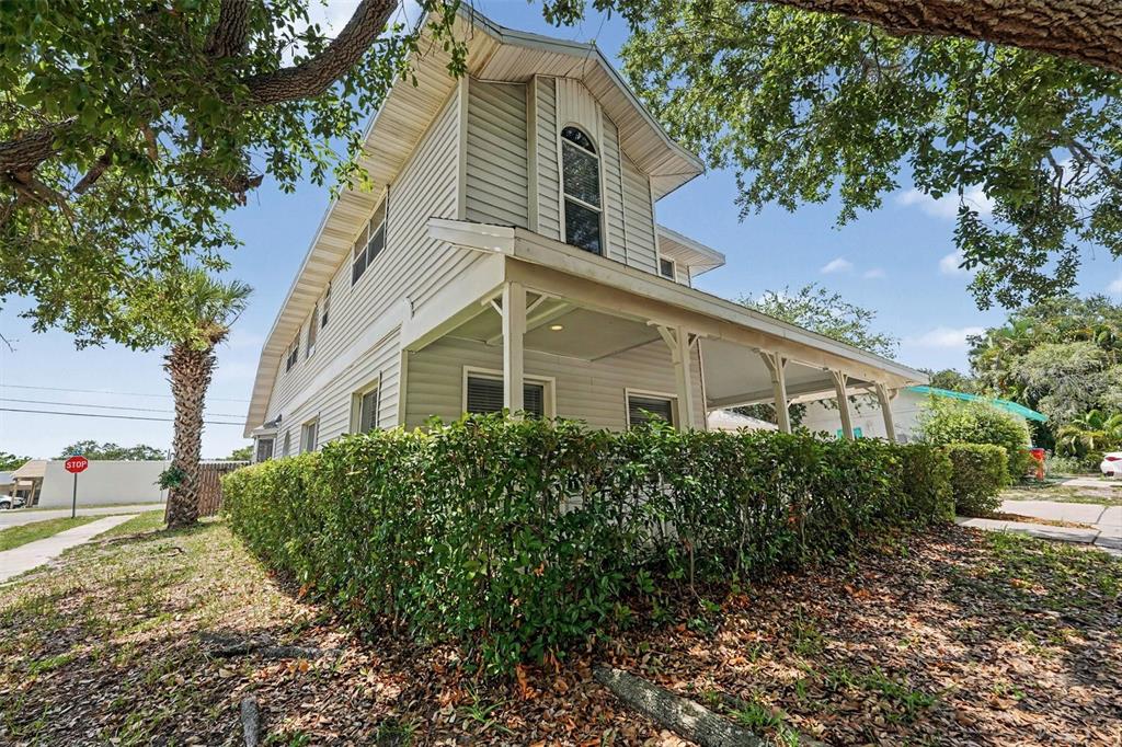 A two-story house with light-colored siding and a covered front porch behind a hedge — 9160 136TH WAY, SEMINOLE, FL