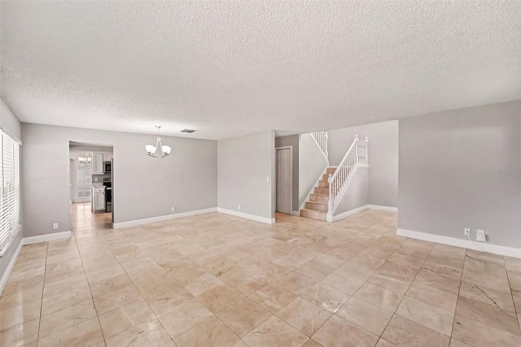 An open-concept living area features light-colored tile flooring, gray walls, and a staircase — 9160 136TH WAY, SEMINOLE, FL