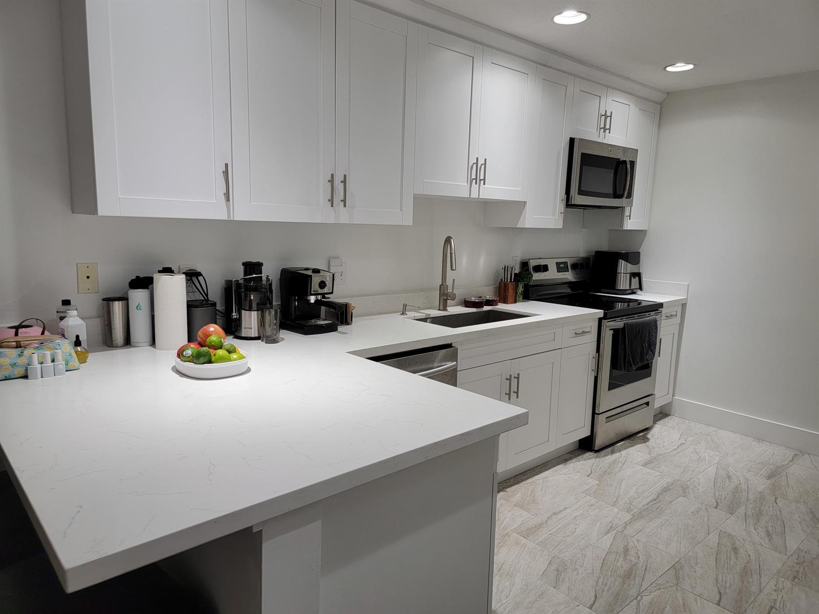 A modern kitchen features white cabinets, quartz countertops, stainless steel appliances, and light tile flooring — 12574 Westhampton Circle # I, Wellington FL 33414, WELLINGTON, FL