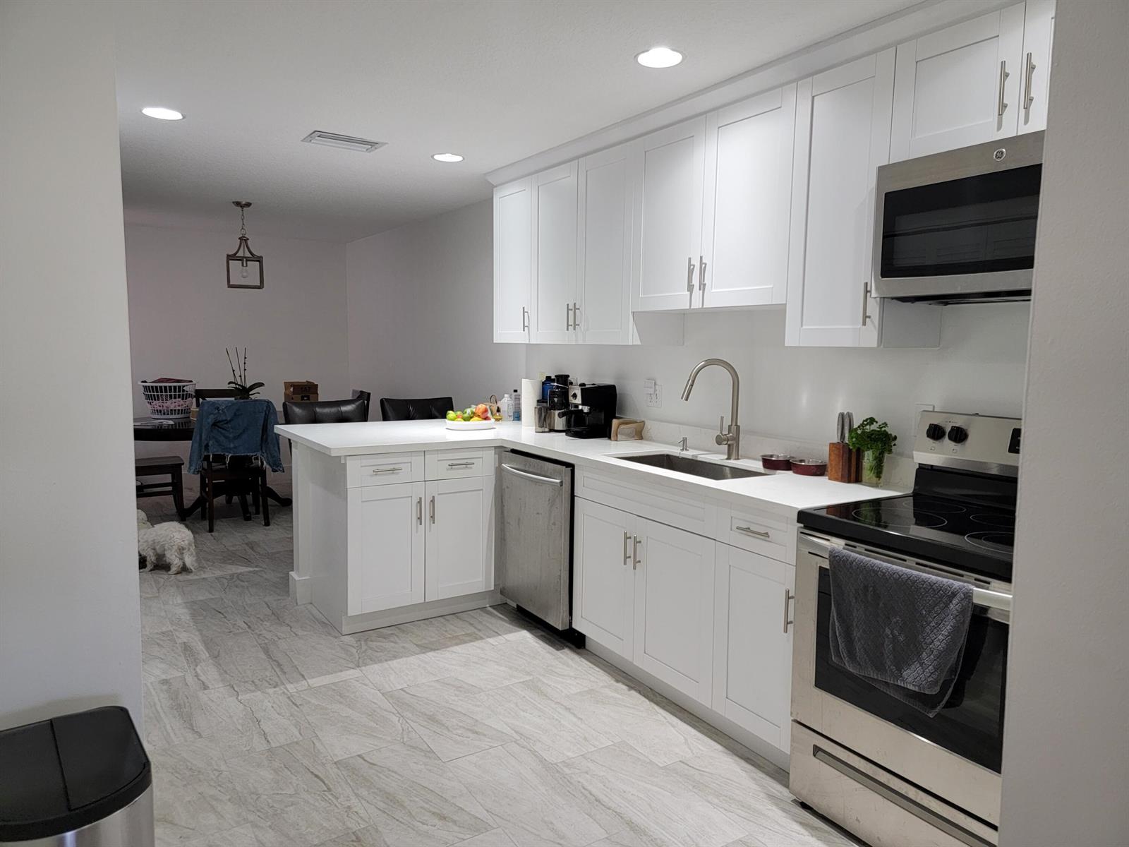 A modern kitchen features white cabinets, stainless steel appliances, and light-colored tile flooring — 12574 Westhampton Circle # I, Wellington FL 33414, WELLINGTON, FL