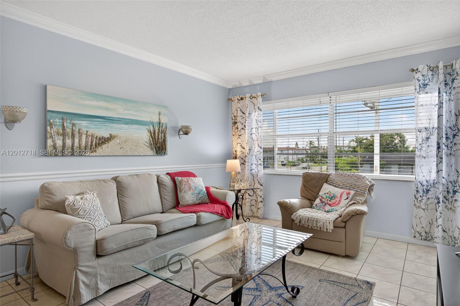 A living room features a beige sofa, a glass coffee table, and a window with curtains — 4451 NW 16th St # K208, Lauderhill FL 33313, LAUDERHILL, FL