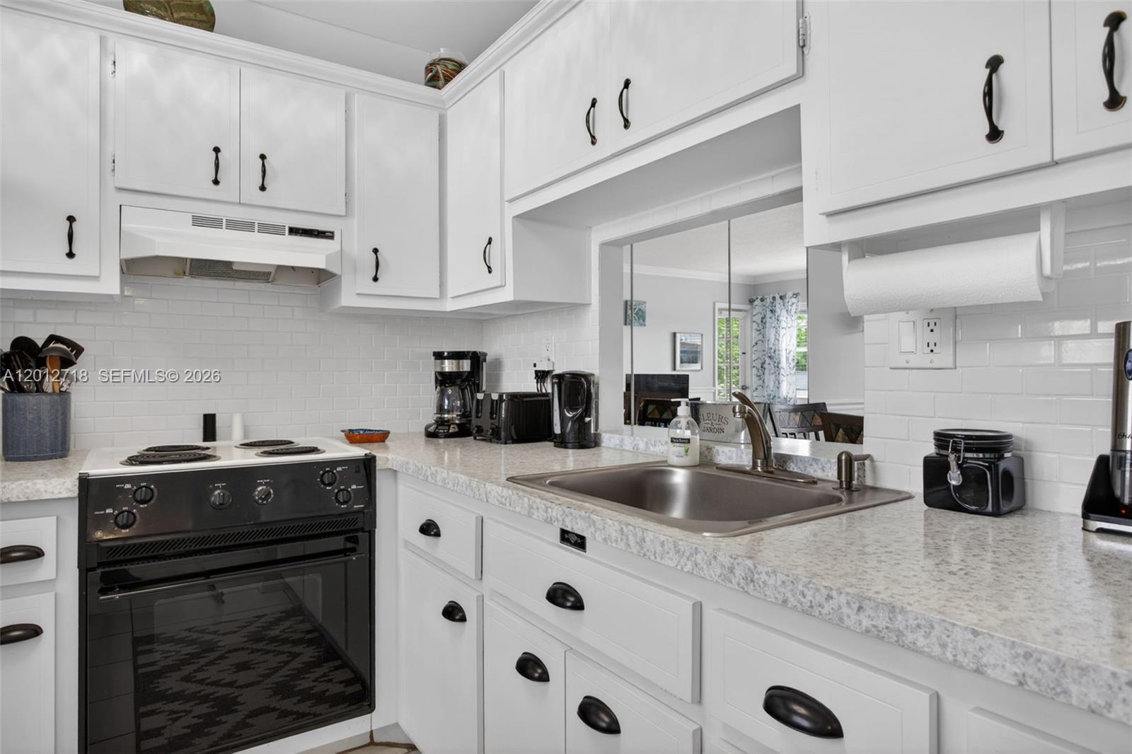 A kitchen features white cabinetry, a black stove, a stainless steel sink, and subway tile — 4451 NW 16th St # K208, Lauderhill FL 33313, LAUDERHILL, FL