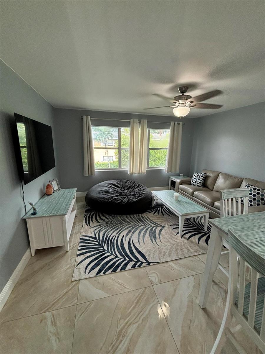 A living room features light gray walls, tile flooring, a beanbag chair, and a television — 440 SE 2nd Avenue # 21, Deerfield Beach FL 33441, DEERFIELD BEACH, FL