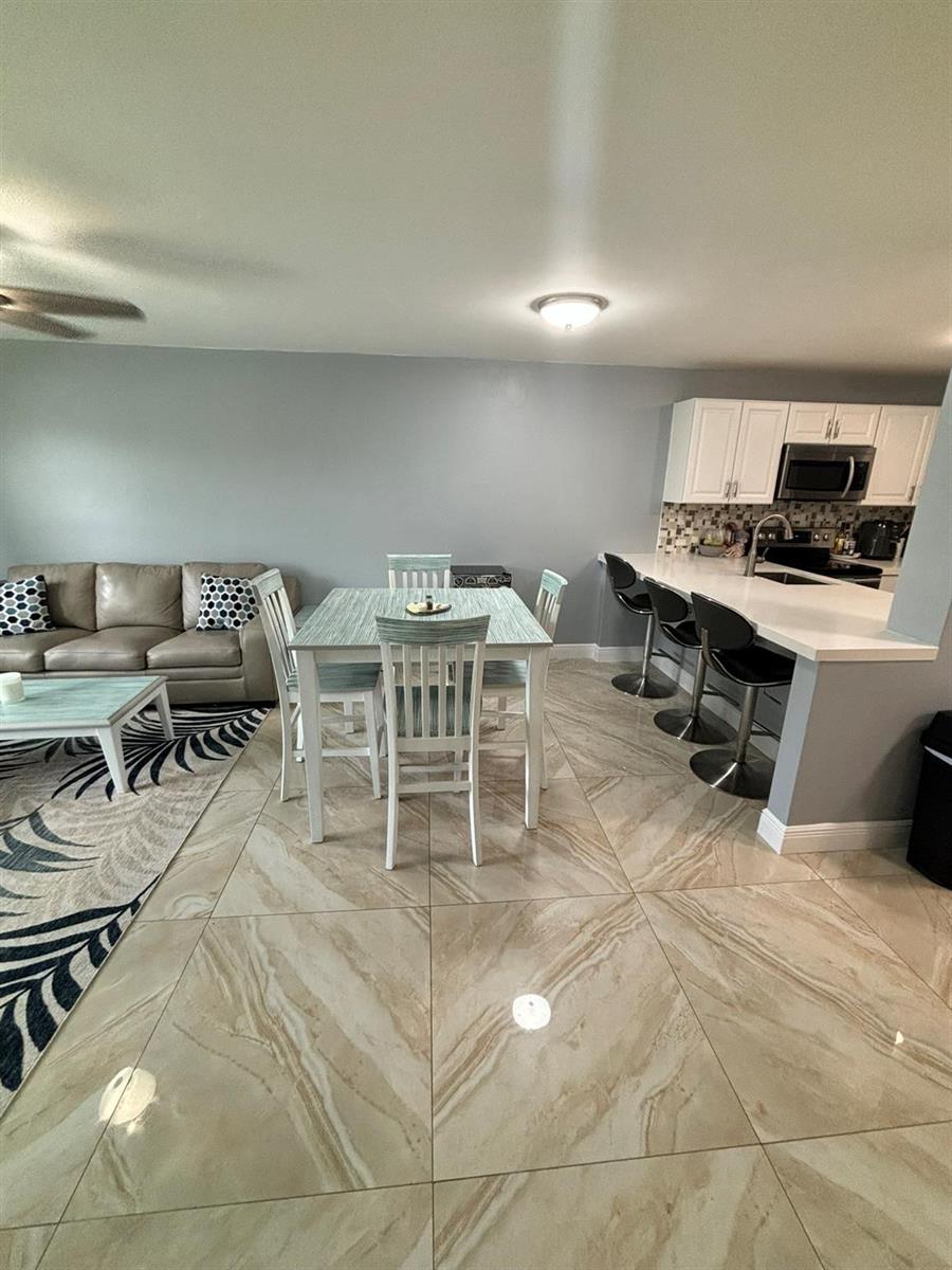 A dining area with a table and chairs sits adjacent to a kitchen with bar seating — 440 SE 2nd Avenue # 21, Deerfield Beach FL 33441, DEERFIELD BEACH, FL
