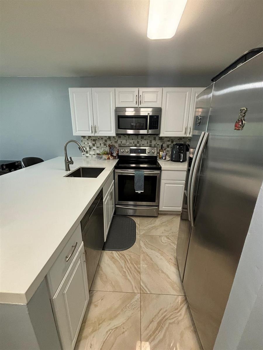 A kitchen features white cabinets, stainless steel appliances, a quartz countertop, and light-colored tile flooring — 440 SE 2nd Avenue # 21, Deerfield Beach FL 33441, DEERFIELD BEACH, FL