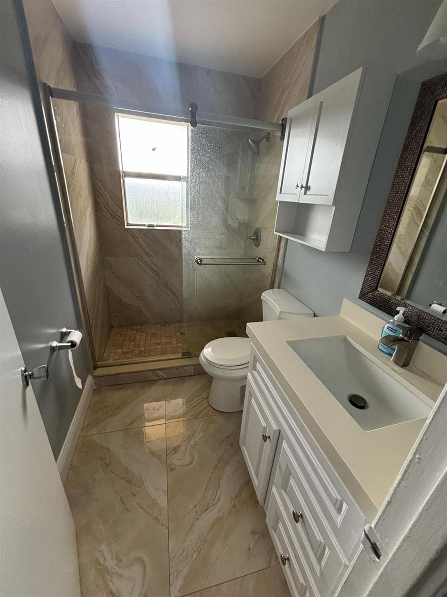A bathroom features a glass-enclosed shower, a white vanity, and light-colored tile flooring — 440 SE 2nd Avenue # 21, Deerfield Beach FL 33441, DEERFIELD BEACH, FL