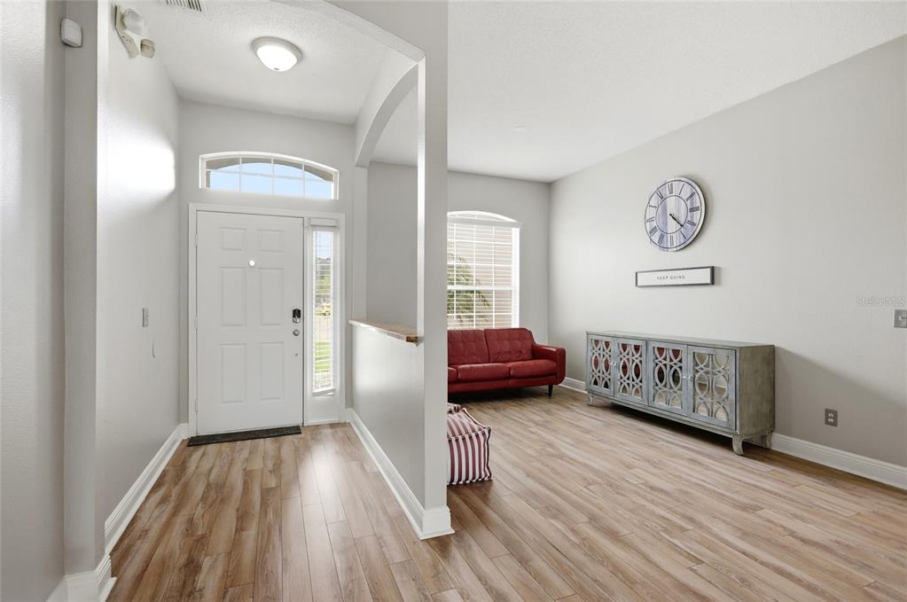 An entryway leads into a living area with light wood flooring, a red sofa, and cabinetry — 340 BALLYSHANNON DRIVE, DAVENPORT, FL