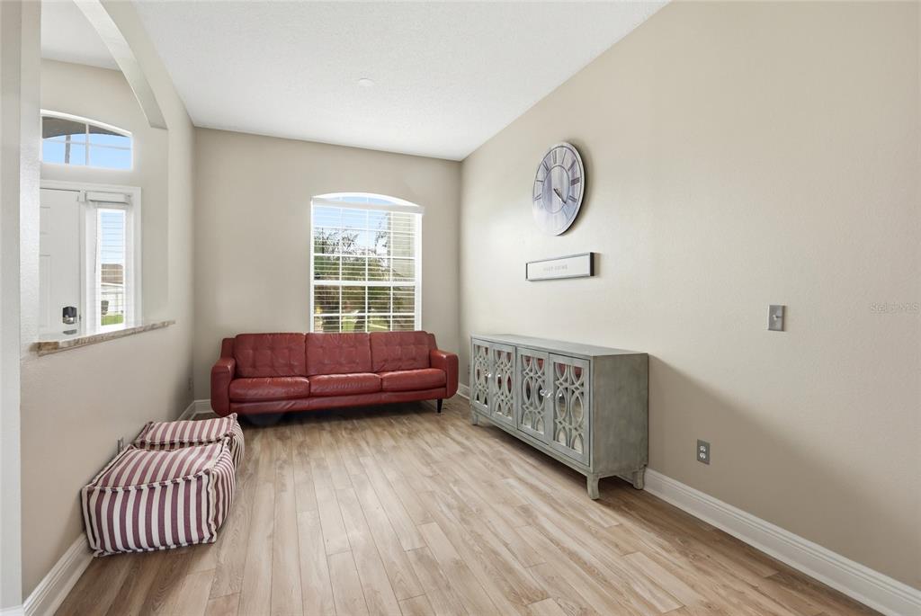 A living room features a red sofa, a grey sideboard, and a large wall clock — 340 BALLYSHANNON DRIVE, DAVENPORT, FL