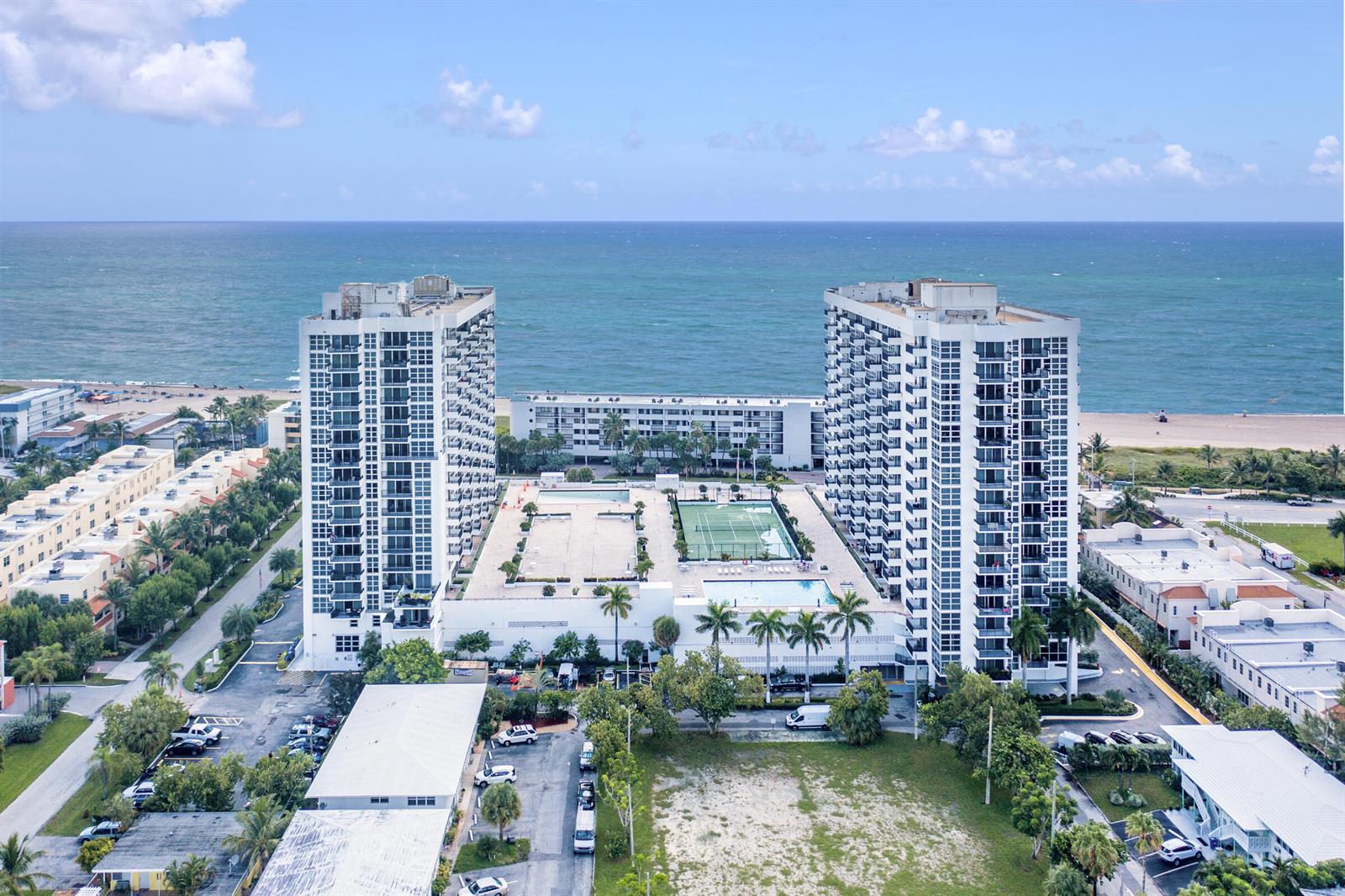 An aerial view shows two high-rise apartment buildings with a pool and tennis court between them — 531 N Ocean Boulevard # 1811, Pompano Beach FL 33062, POMPANO BEACH, FL