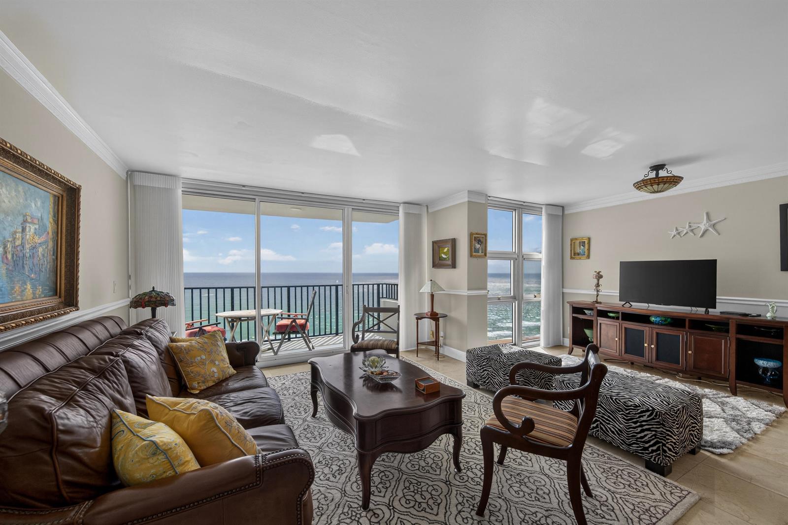 A living room features a leather sofa, coffee table, and large windows overlooking the ocean — 531 N Ocean Boulevard # 1811, Pompano Beach FL 33062, POMPANO BEACH, FL