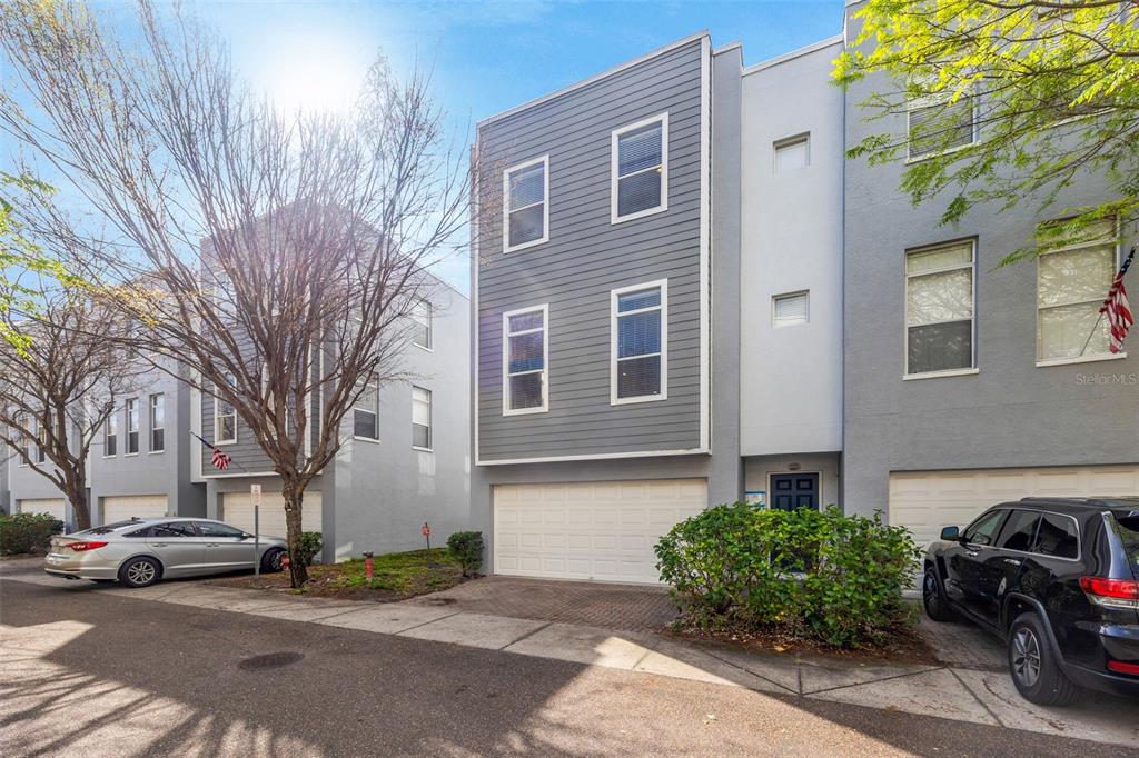 A three-story townhouse with gray siding, a two-car garage, and a paved driveway — 4526 BAY SPRING COURT, TAMPA, FL
