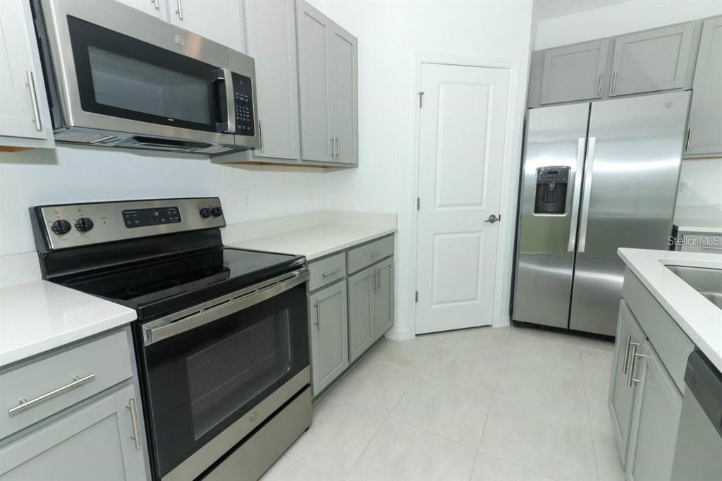 A kitchen features gray cabinets, stainless steel appliances, and white countertops — 165 CITRINE LOOP, KISSIMMEE, FL