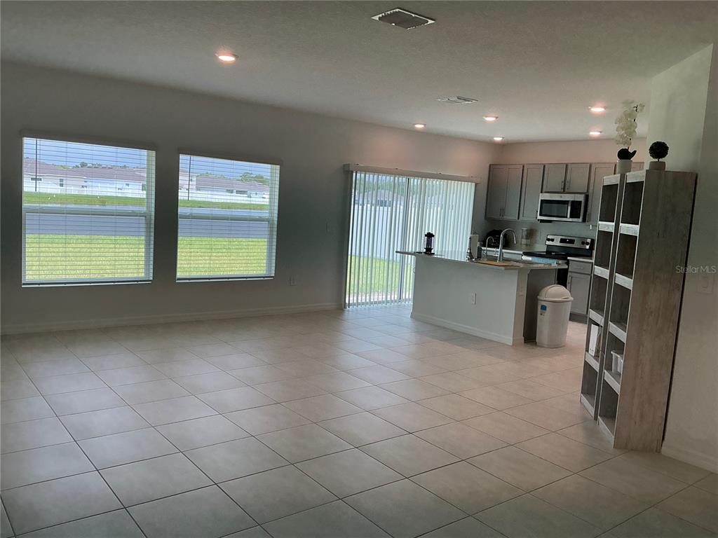An open-concept kitchen with gray cabinets and a tile floor overlooks a living area — 165 CITRINE LOOP, KISSIMMEE, FL