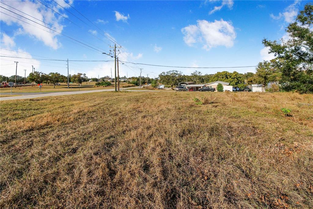 A wide, grassy vacant lot sits beside a paved road with houses in the distance — SR-17 SCENIC HIGHWAY N, HAINES CITY, FL