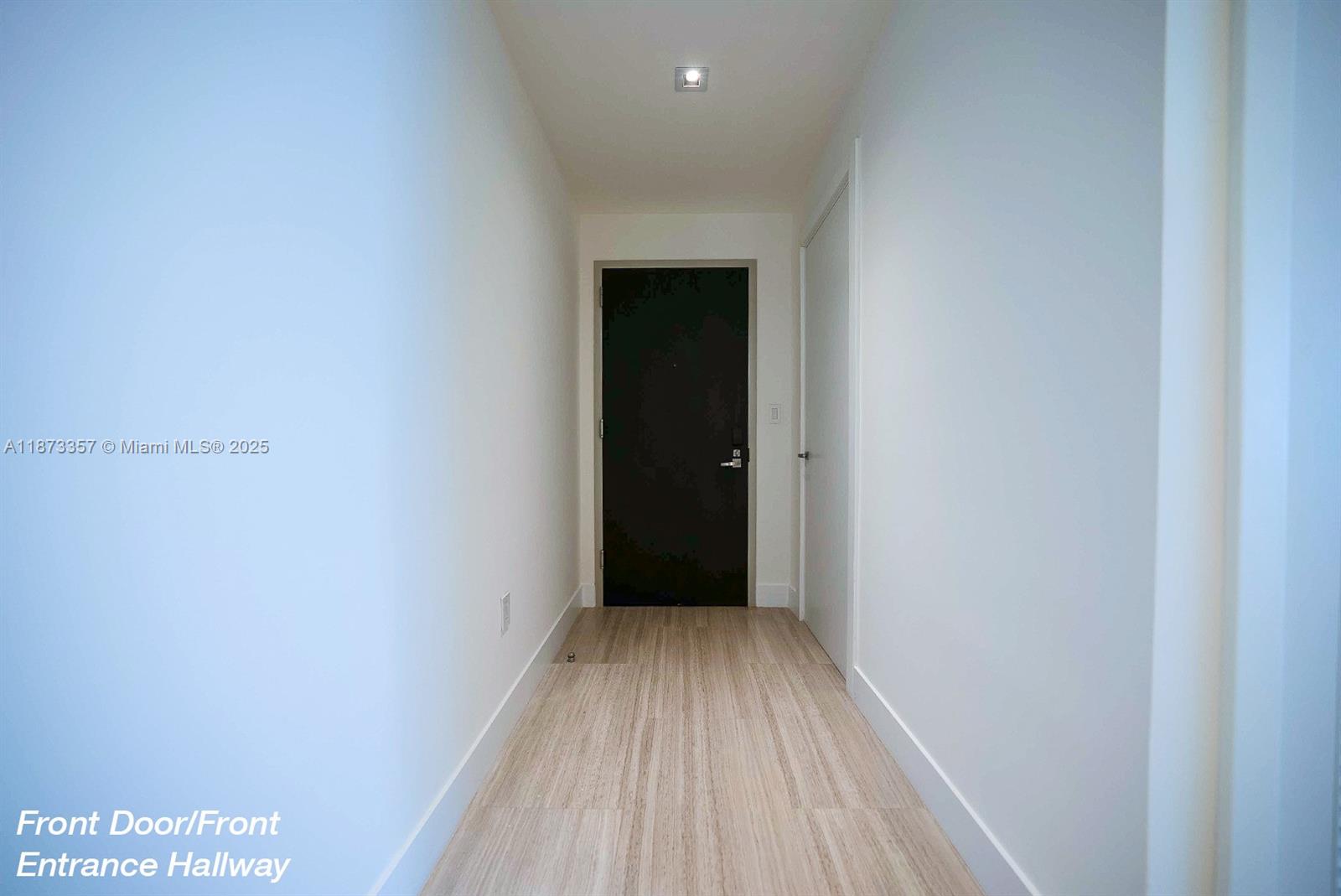 A narrow hallway features light wood-look flooring, white walls, and a dark front door — 1451 Brickell Ave # 2706, Miami FL 33131, MIAMI, FL