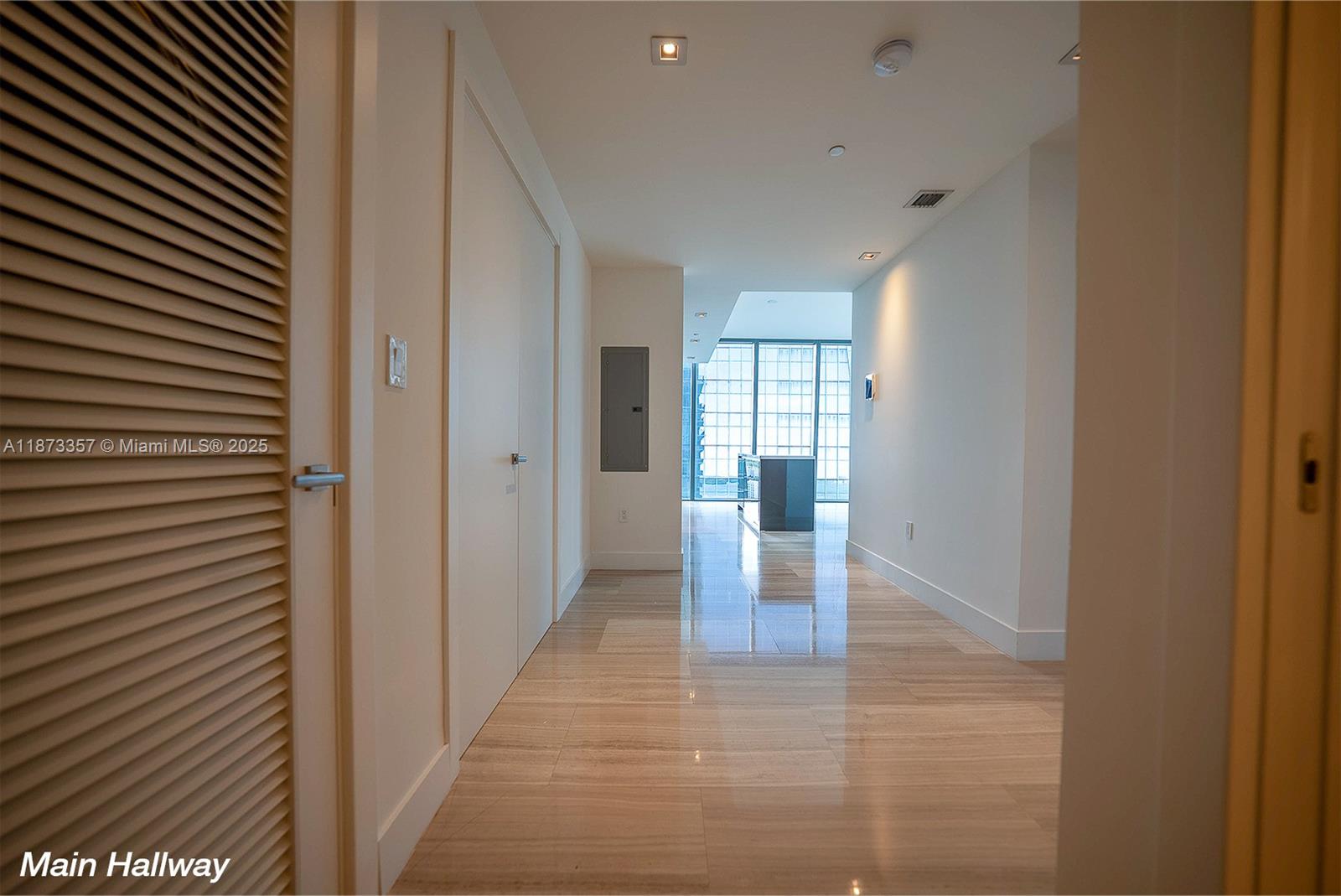 A bright hallway features light-colored tile flooring, white walls, and a view toward windows — 1451 Brickell Ave # 2706, Miami FL 33131, MIAMI, FL