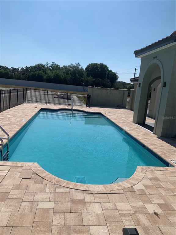 A rectangular swimming pool is surrounded by a paved deck and a black metal fence — 21004 ISOLA BELLA CIRCLE, VENICE, FL