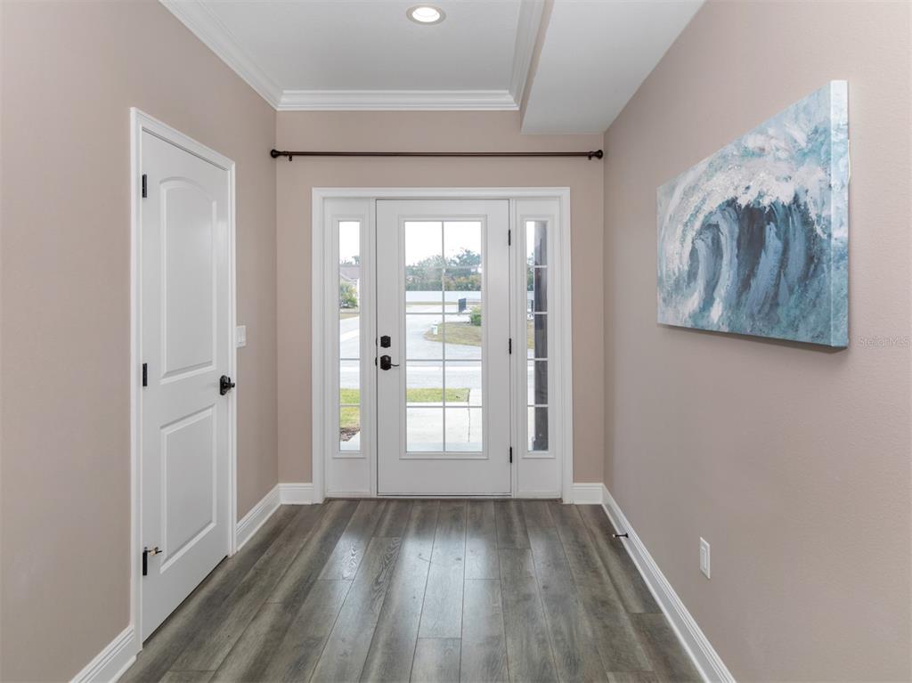 An entryway features light-colored walls, wood-look flooring, a white front door, and wall art — 21004 ISOLA BELLA CIRCLE, VENICE, FL