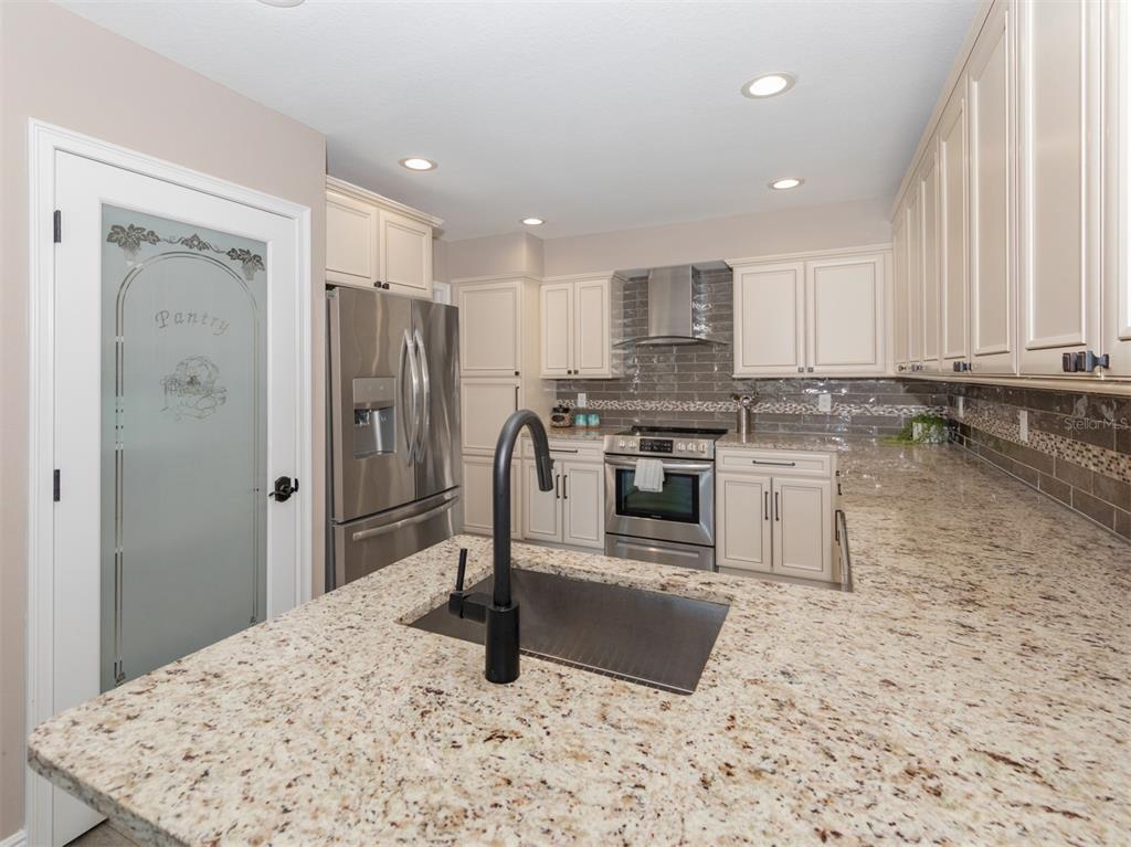 A kitchen features granite countertops, a central island with a sink, and stainless steel appliances — 21004 ISOLA BELLA CIRCLE, VENICE, FL