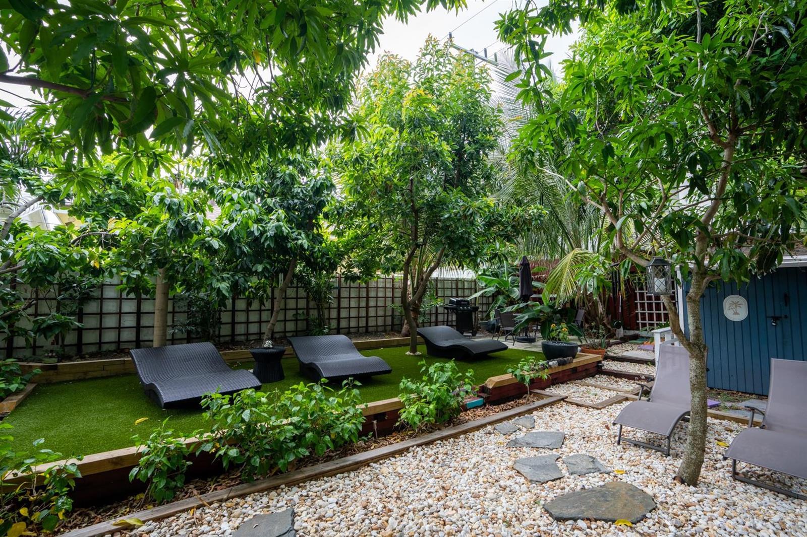 A backyard features a raised artificial turf area with lounge chairs and a gravel patio — 1944 NE 5th Street, Deerfield Beach FL 33441, DEERFIELD BEACH, FL