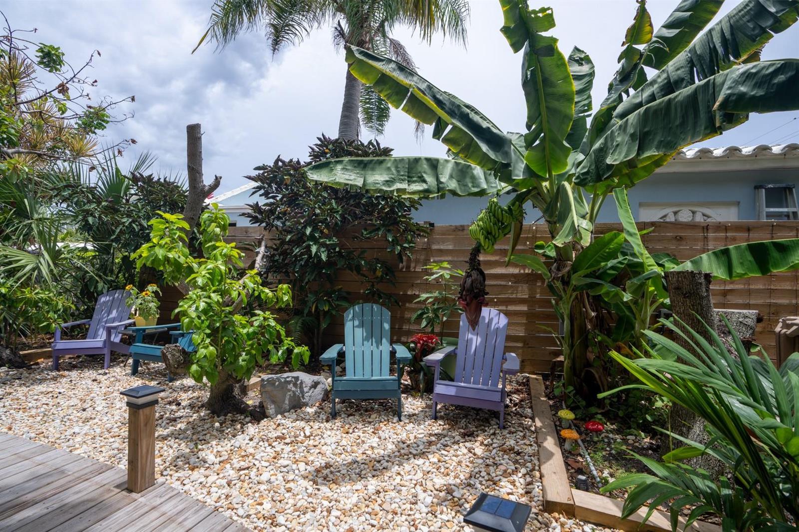 A backyard patio features gravel ground, three Adirondack chairs, and a banana tree with fruit — 1944 NE 5th Street, Deerfield Beach FL 33441, DEERFIELD BEACH, FL