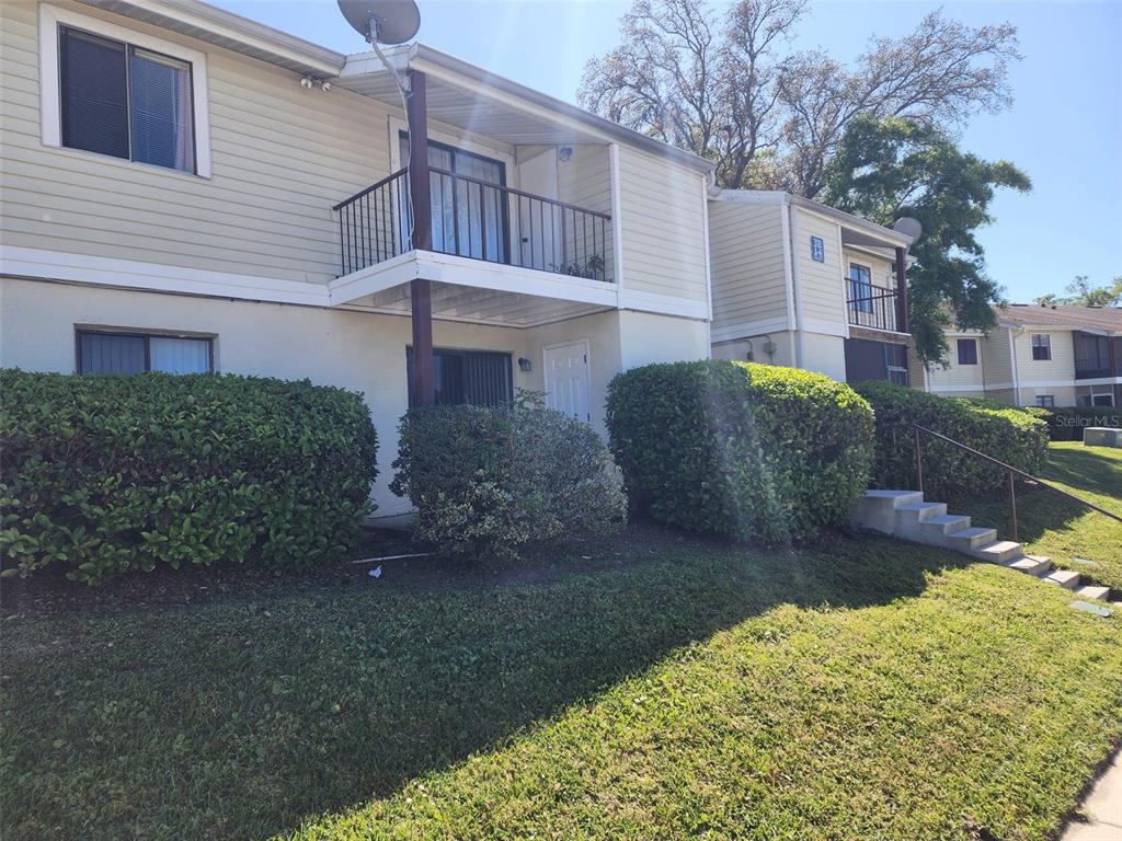 Exterior view of a two-story apartment building with balconies, beige siding, and landscaped bushes — 310 CHEROKEE COURT UNIT F, ALTAMONTE SPRINGS, FL