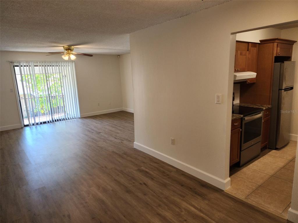 A living area with wood-look flooring leads to a kitchen featuring wood cabinets and appliances — 310 CHEROKEE COURT UNIT F, ALTAMONTE SPRINGS, FL