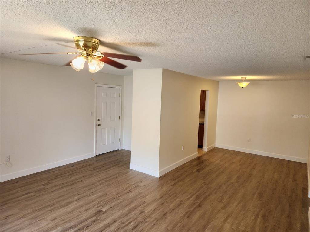 A living room features wood-look flooring, a ceiling fan, and a white entry door — 310 CHEROKEE COURT UNIT F, ALTAMONTE SPRINGS, FL