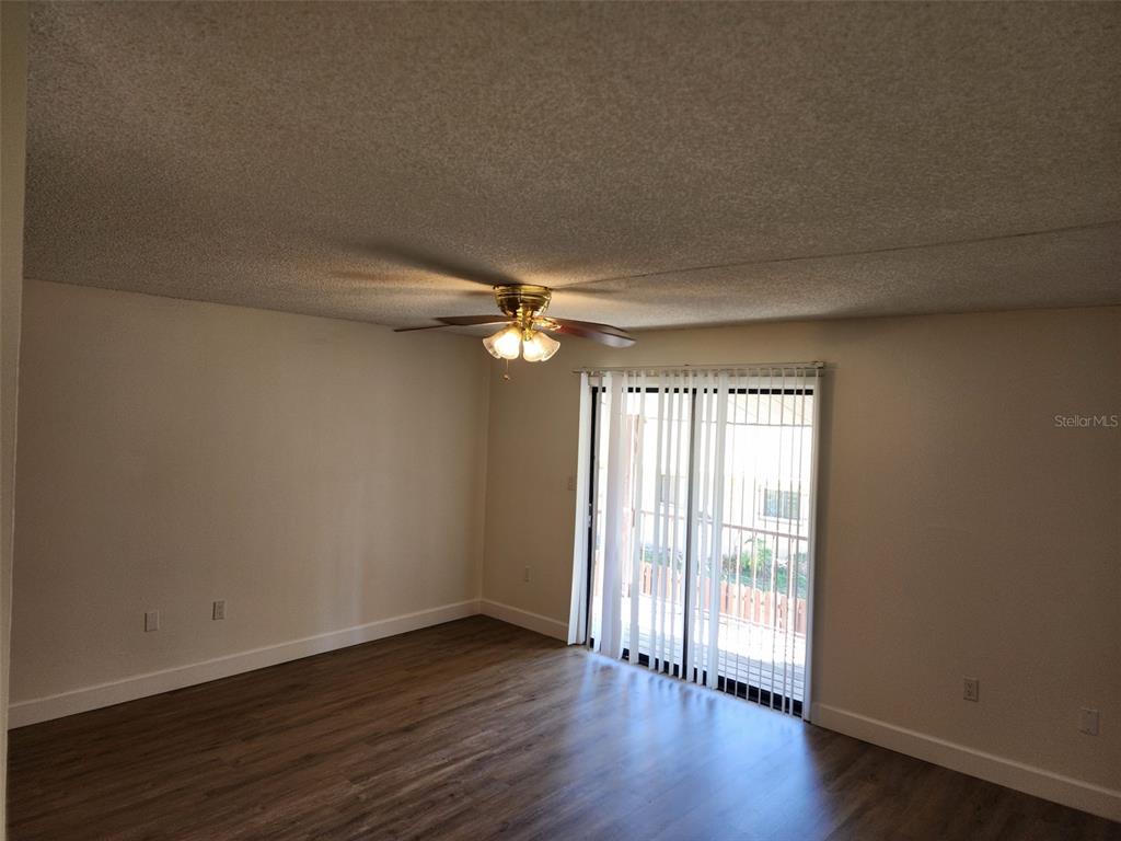 An empty room features wood-look flooring, a ceiling fan, and a sliding glass door — 310 CHEROKEE COURT UNIT F, ALTAMONTE SPRINGS, FL