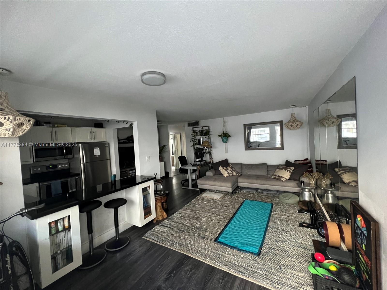 An open-concept living room features a kitchen with a breakfast bar, gray sofa, and rug — 221 Meridian Ave # 206, Miami Beach FL 33139, MIAMI BEACH, FL