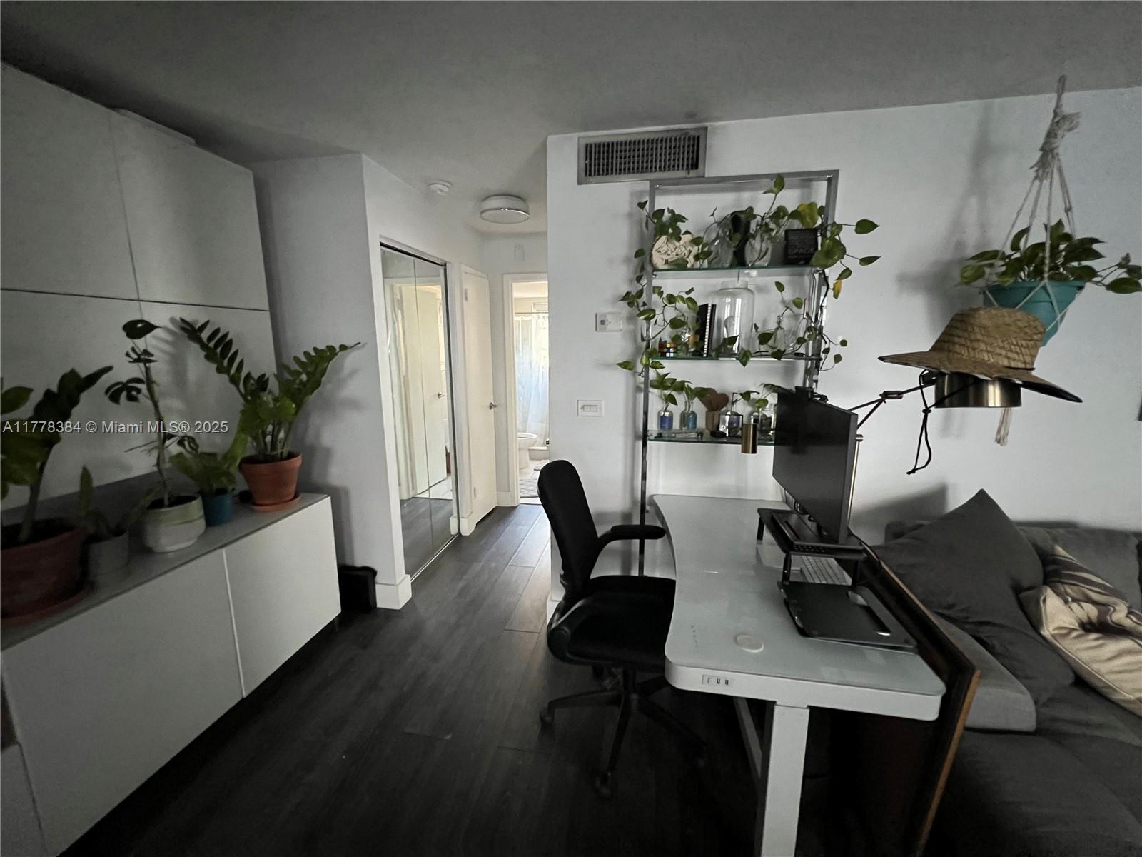 A home office area features a desk, shelving, plants, and dark wood-look flooring — 221 Meridian Ave # 206, Miami Beach FL 33139, MIAMI BEACH, FL