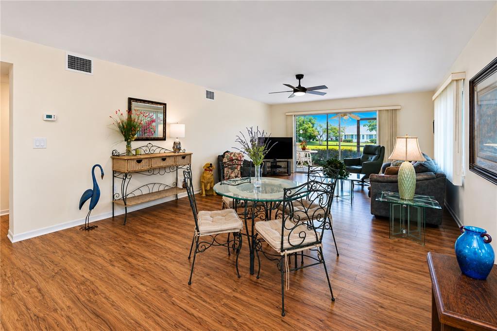A living and dining area features wood-look flooring, a glass dining table, and sliding glass doors — 4853 INDEPENDENCE DRIVE, BRADENTON, FL