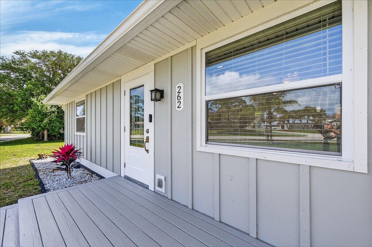 A gray house exterior features a white front door, a wooden porch, and a large window — 262 Easy Street, Sebastian FL 32958, SEBASTIAN, FL