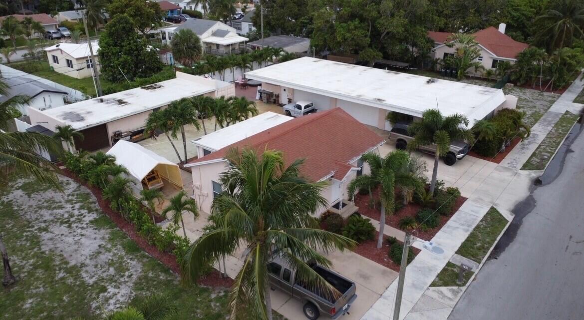 An aerial view shows a residential property with a house, detached garages, and palm trees — 505 24th Avenue N, FL 33460, FL