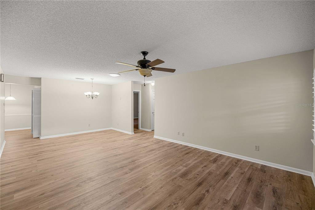 An empty living room with light wood-look flooring, beige walls, and a ceiling fan — 9357 SW 82ND TERRACE UNIT C, OCALA, FL