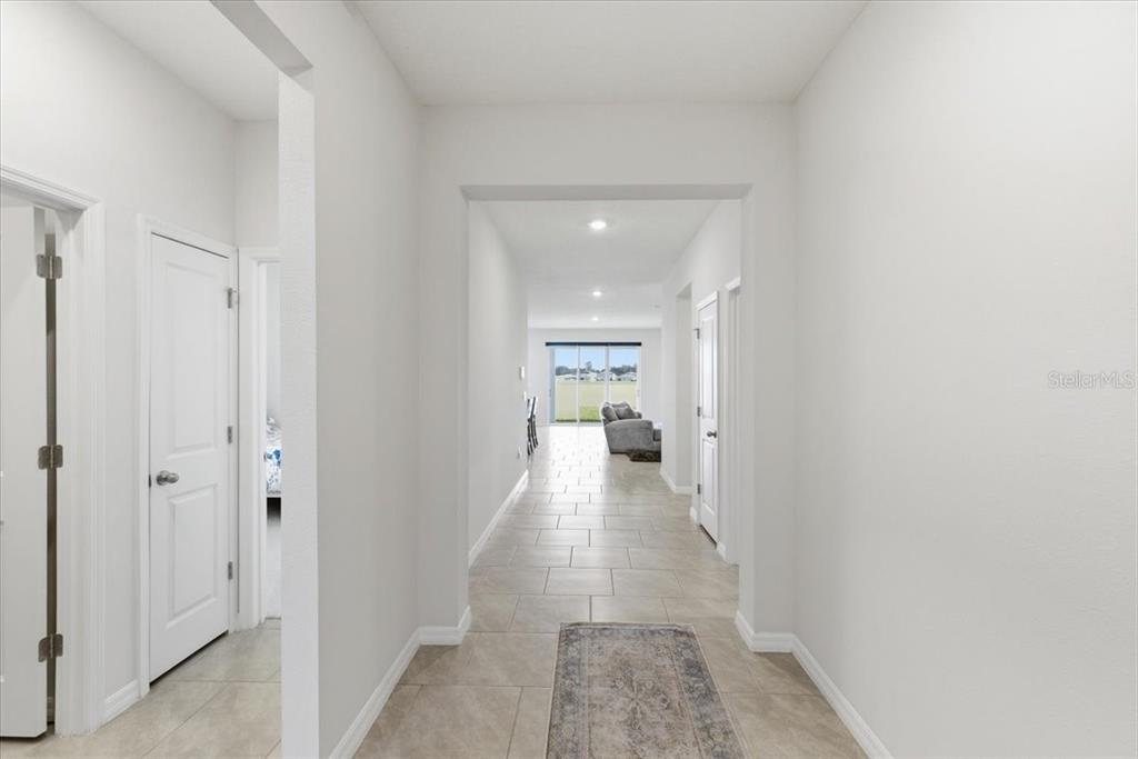 A tiled hallway leads from a foyer toward a living area with a sliding door — 1413 TROPICAL OASIS AVENUE, PLANT CITY, FL