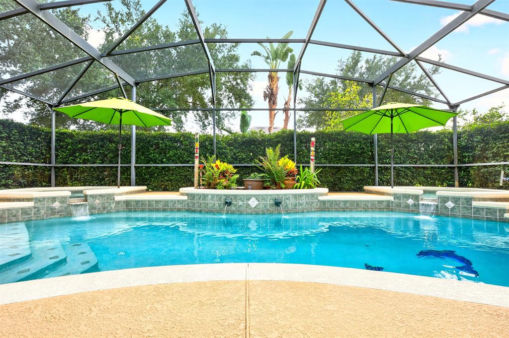 A screened-in swimming pool features two green umbrellas and a tiled water feature — 10020 RUSTIC RIDGE COURT, ORLANDO, FL