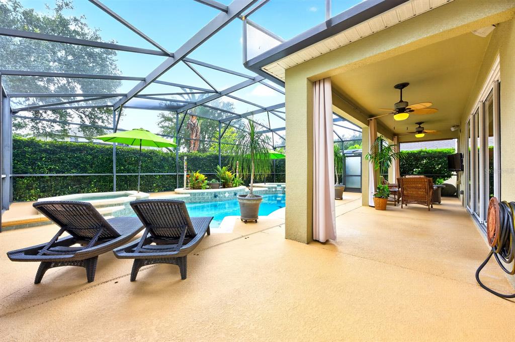 A covered patio with lounge chairs overlooks a swimming pool inside a screened-in enclosure — 10020 RUSTIC RIDGE COURT, ORLANDO, FL