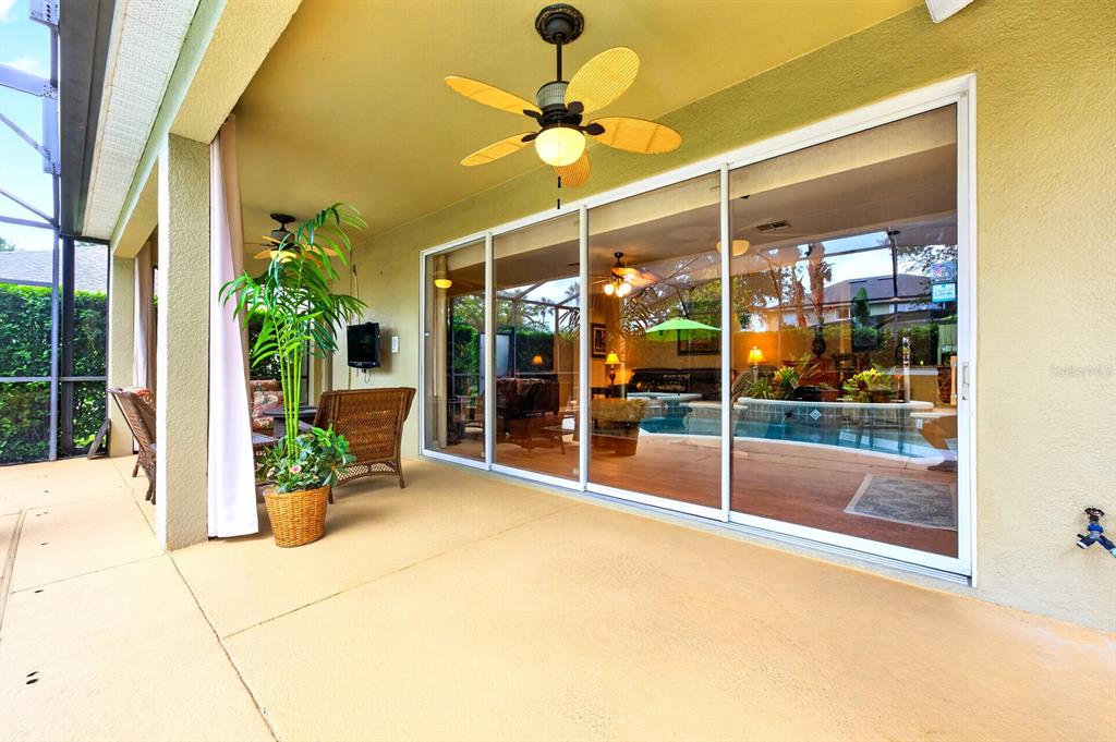 A covered patio features a ceiling fan, wicker furniture, a potted plant, and sliding glass doors — 10020 RUSTIC RIDGE COURT, ORLANDO, FL