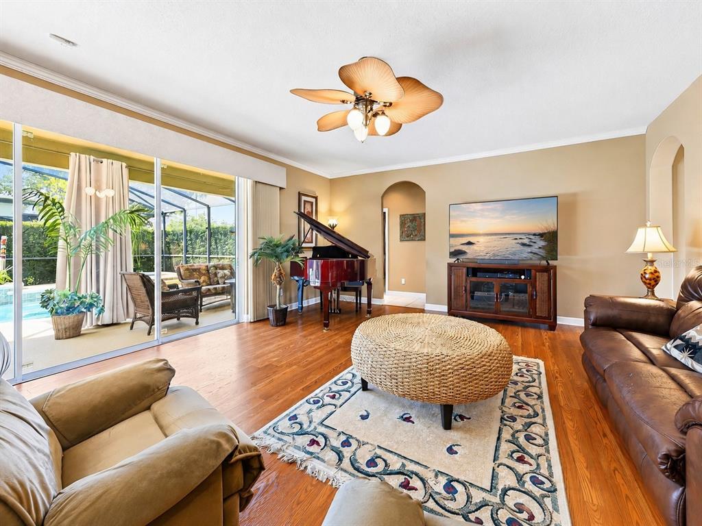 A living room features hardwood floors, a grand piano, a television, and a sliding glass door — 10020 RUSTIC RIDGE COURT, ORLANDO, FL