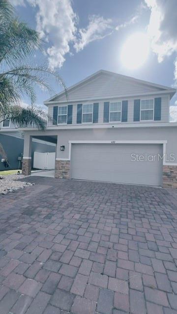 A two-story house with a gray garage, stone accents, and a paved driveway — 680 BLOOM TERRACE, DAVENPORT, FL