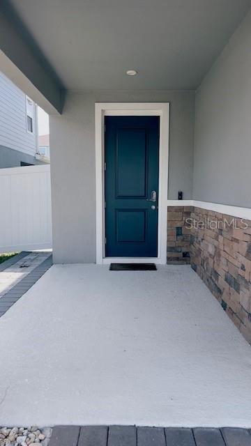A covered concrete porch leads to a dark blue front door with stone veneer siding — 680 BLOOM TERRACE, DAVENPORT, FL