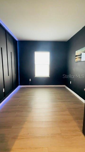 A bedroom with dark walls, light wood-look flooring, and a wall with vertical accent panels — 680 BLOOM TERRACE, DAVENPORT, FL