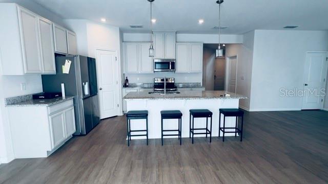 A modern kitchen features white cabinetry, granite countertops, a center island, and stainless steel appliances — 680 BLOOM TERRACE, DAVENPORT, FL