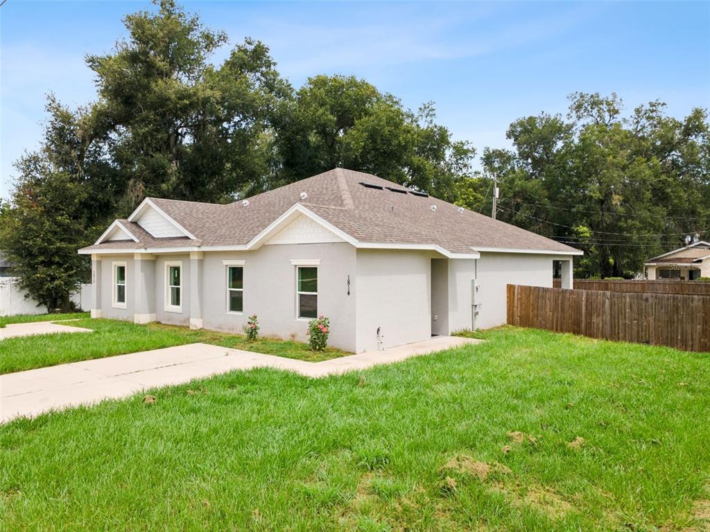 A single-story house with a gray stucco exterior, a shingled roof, and a concrete driveway — 1810 DUNBAR STREET, BARTOW, FL