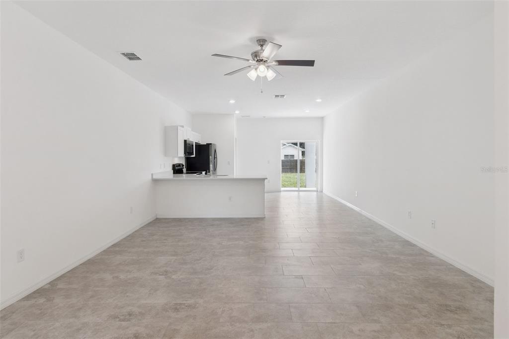 An open-concept living area with white walls, tile flooring, a ceiling fan, and a kitchen — 1810 DUNBAR STREET, BARTOW, FL