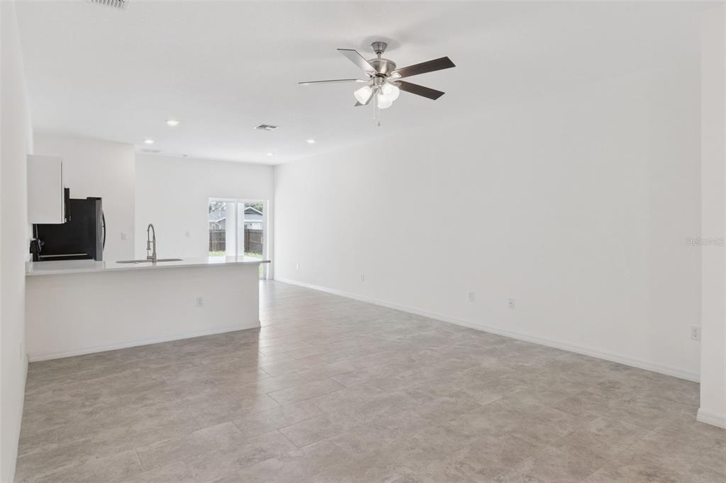 An open-concept living area features light gray tile flooring, white walls, and a kitchen island — 1810 DUNBAR STREET, BARTOW, FL