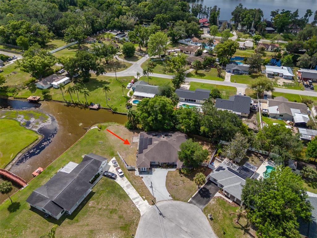 An aerial view shows a residential house with solar panels and a backyard near water — 18853 TRACER DRIVE, LUTZ, FL